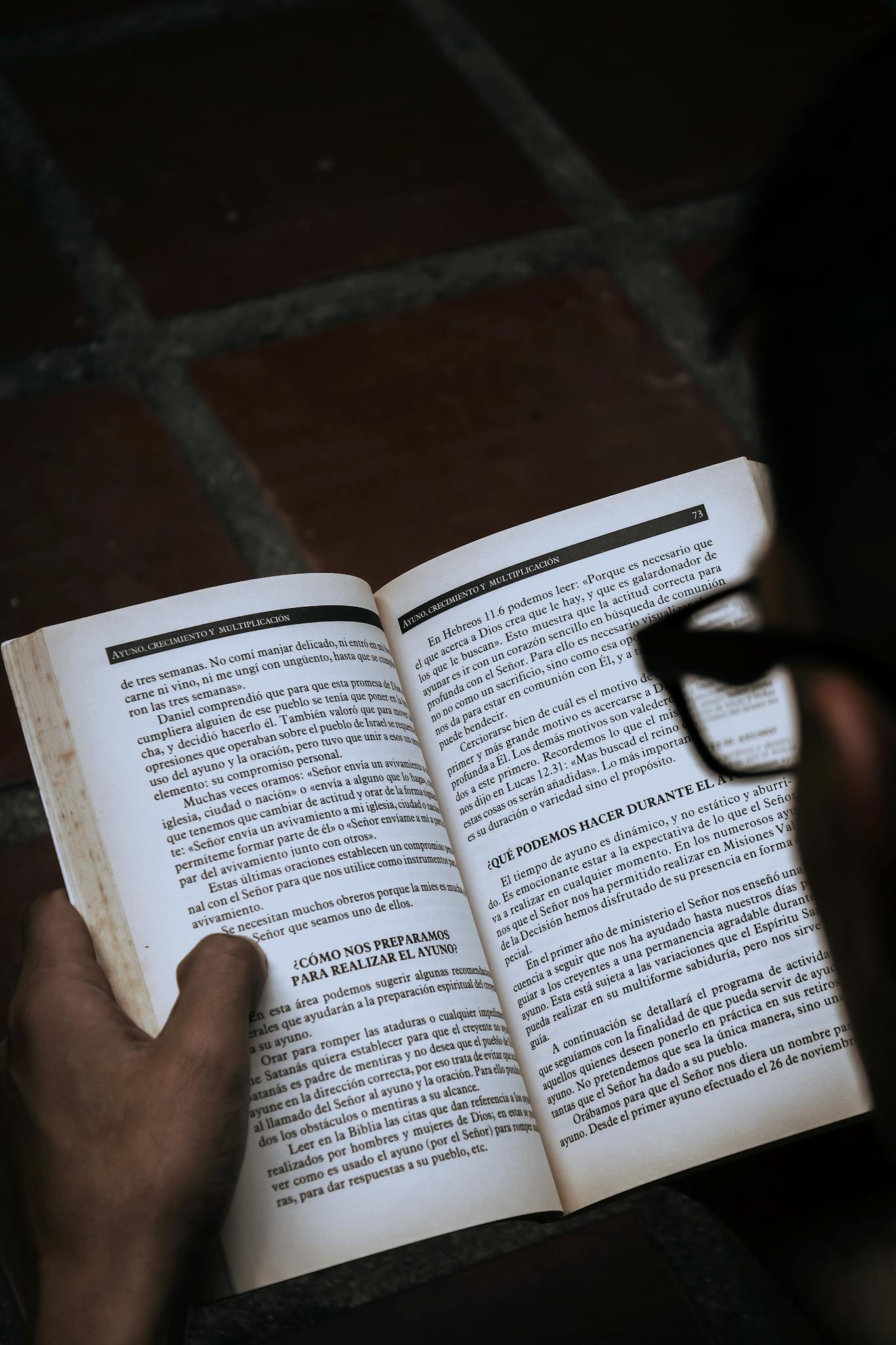 A person reads an open book indoors, reflecting concentration and leisure in Mérida, Venezuela.